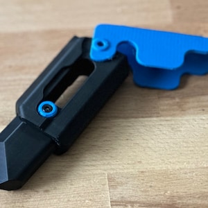 May include: A black and blue utility knife with a sharp blade and a safety lock. The knife has a textured grip and a blue plastic handle.