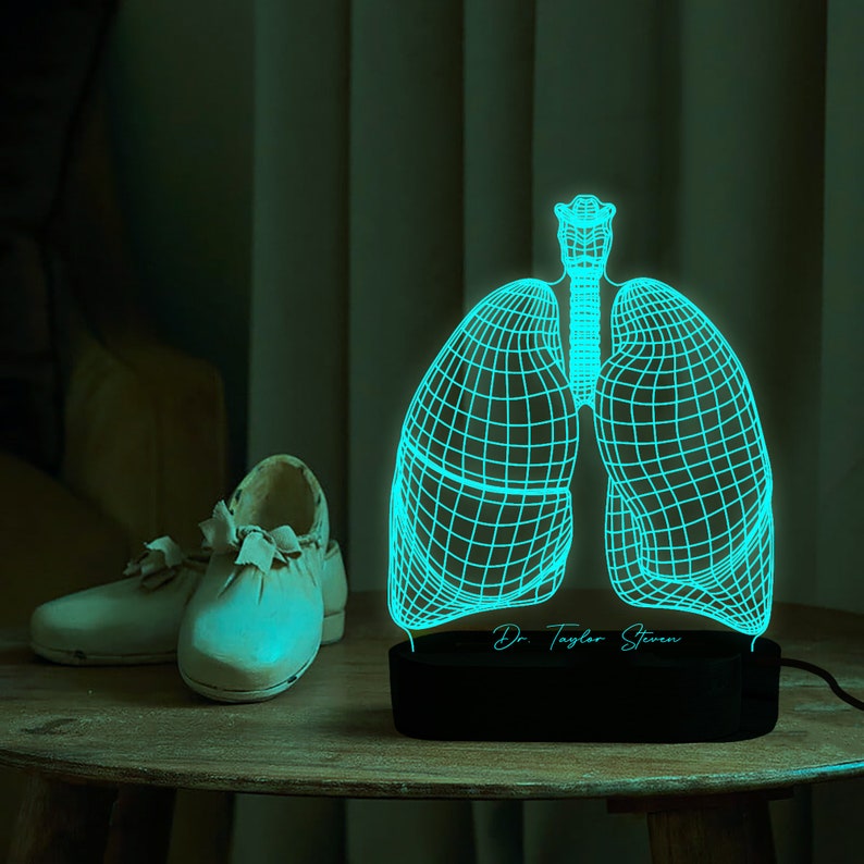 May include: A 3D printed, turquoise blue, anatomical model of human lungs with a black base. The base has the text "Dr. Taylor Steven" engraved on it.