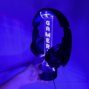 May include: A black headset stand with a clear acrylic base and a white LED light that displays the word "GAMER".