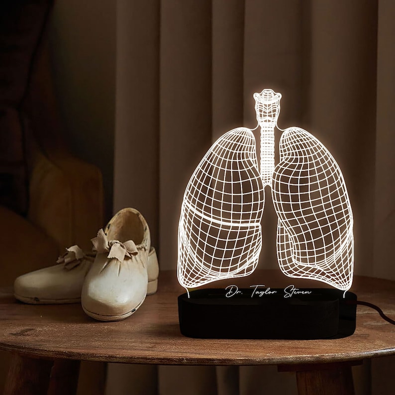 May include: A white 3D printed anatomical model of human lungs on a black base with a personalized inscription "Dr. Taylor Steven".