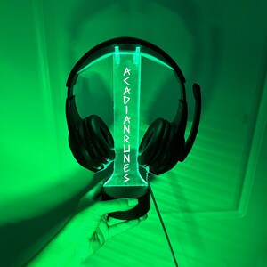 May include: A black headset with a green LED light stand that says "Acadian Runes".