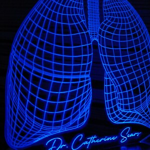 May include: A blue 3D printed light sculpture of a pair of lungs with a wireframe design. The base of the sculpture has the text "Dr. Catherine Sears" in a cursive font.