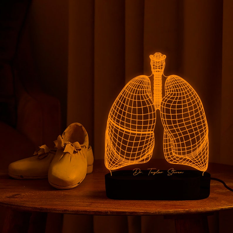 May include: A 3D printed, orange glow-in-the-dark lamp shaped like a human lung. The lamp has a black base with the text "Dr. Taylor Steven" on it.