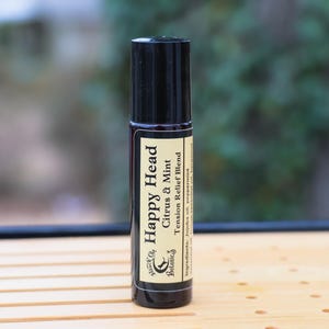 Peut inclure: Un flacon noir à bille avec une étiquette jaune sur laquelle est inscrit "Happy Head Citrus & Mint Tension Relief Blend".