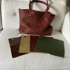 May include: A brown leather tote bag with a woven design. Four leather swatches in brown, green, tan, and burgundy are laid out on a white surface.