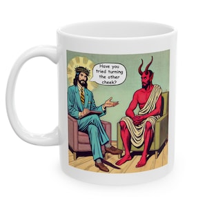 Könnte beinhalten: Weiße Keramiktasse mit einer Comic-Illustration von Jesus und dem Teufel in einer Therapiesitzung. Der Text lautet "Hast du schon versucht, die andere Wange hinzuhalten?"