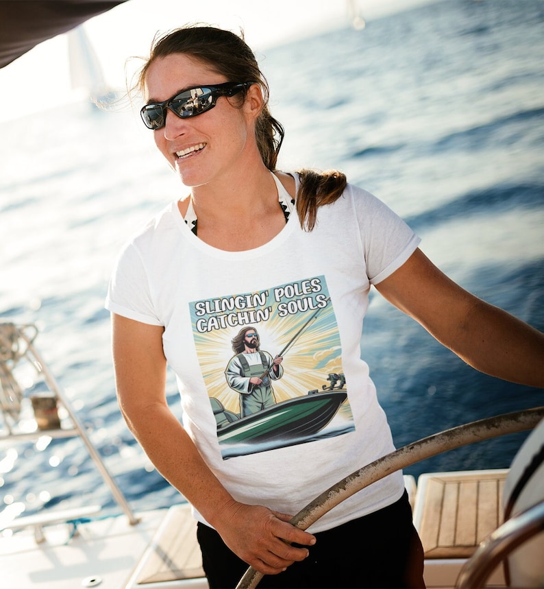 May include: White t-shirt with a graphic of a man fishing from a boat. The graphic has the text "Slingin' Poles Catchin' Souls".