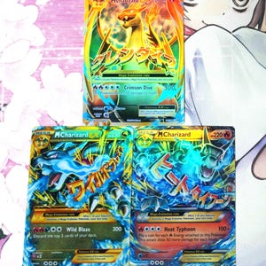 May include: Three Mega Charizard EX Pokémon trading cards. The top card features a golden Charizard with orange wings and the text "Crimson Dive". The other two cards feature blue Charizards with Japanese text and attack descriptions.