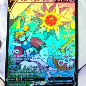 May include: A Starmie V Pokemon card from the Sword & Shield Trading Card Game. The card features a holographic image of Starmie with a blue and yellow color scheme. The card's text reads "Starmie V" and "190 HP".