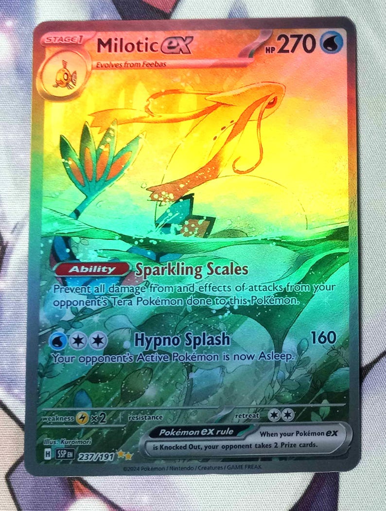 Peut inclure: Une carte de jeu de commerce Pok&eacute;mon holographique repr&eacute;sentant Milotice EX, un Pok&eacute;mon de type eau avec un sch&eacute;ma de couleurs rose, orange et bleu. La carte a une capacit&eacute; d'&eacute;cailles scintillantes et une attaque d'&eacute;claboussure hypnotique. Le num&eacute;ro de la carte est 237/191.