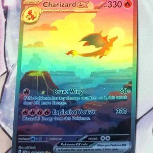 May include: Charizard EX Pokemon card, a stage 2 card with a holographic background. The card features a red, orange, and yellow Charizard flying in the air. The card has a HP of 330 and has two attacks: Brave Wing and Explosive Vortex.