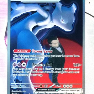 May include: A Pokémon trading card featuring Mewtwo ex, a blue and purple creature, with a character in a suit. The card has text including "Power Saver" and "Erasure Ball". The card is from the Team Rocket set.