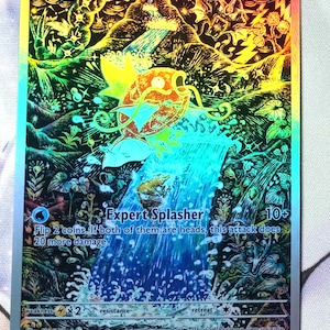 Puede incluir: Una tarjeta Pok&eacute;mon hologr&aacute;fica de Magikarp con una vibrante escena de cascada. La tarjeta presenta el texto "Magikarp" y "Expert Splasher", junto con detalles de ataque y un valor de 30 HP. Es un art&iacute;culo de colecci&oacute;n.