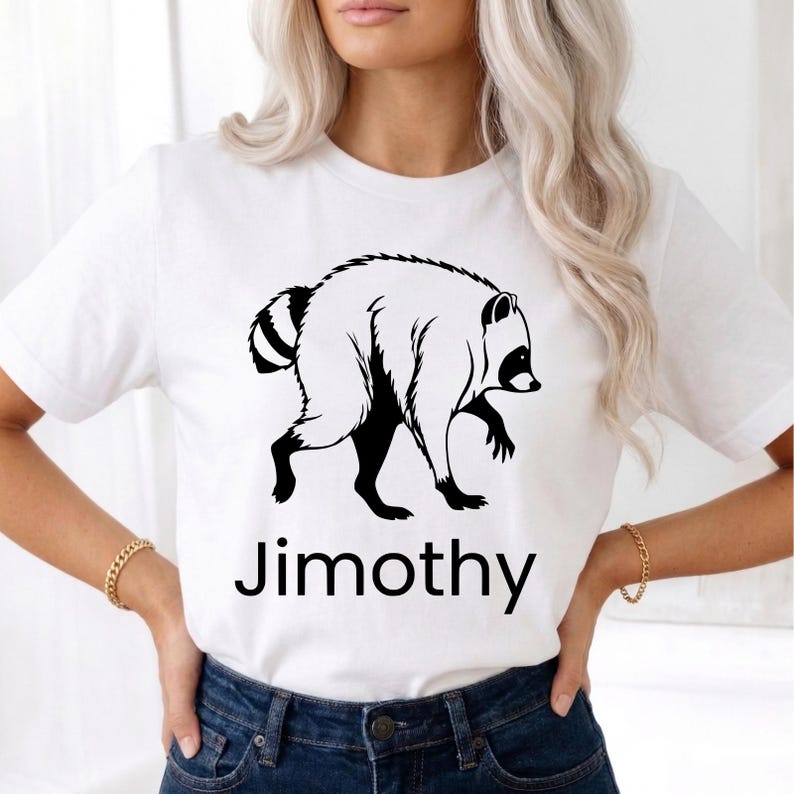 May include: A white short-sleeved t-shirt featuring a black graphic illustration of a raccoon in profile. Below the raccoon, the text Jimothy is printed in a bold, black, sans-serif font. The shirt has a crew neckline and a standard fit.