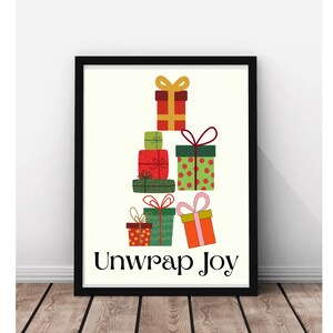May include: A framed print featuring a stack of colorful gift boxes with bows. The gifts are red, green, and orange with various patterns. The text "Unwrap Joy" is displayed in black below the gifts.
