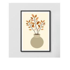 Puede incluir: Una impresión artística enmarcada que presenta un jarrón beige con tallos marrones y hojas naranjas. La obra de arte está sobre un fondo crema y enmarcada en un borde negro. El diseño minimalista es adecuado para la decoración del hogar.