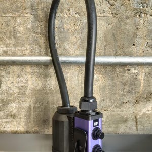 May include: A black electrical cord with a purple control box. The control box has two black knobs and the words "UP" and "DOWN" printed on it. The cord is connected to a black plug.