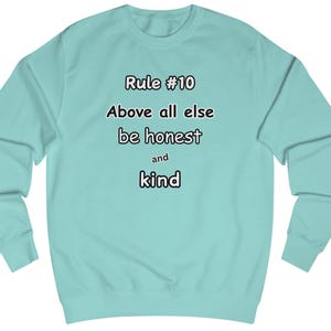 Peut inclure: Un sweat-shirt bleu clair avec le texte "Rule #10 Above all else be honest and kind" imprimé sur le devant.