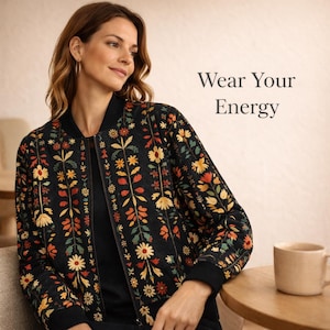 May include: Black bomber jacket with a colorful floral pattern in yellow, orange, and green. The jacket has a black collar, cuffs, and hem. The text "Wear Your Energy" is displayed on the right side of the image.