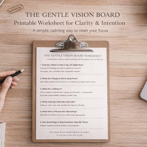 以下が含まれることがあります： 「The Gentle Vision Board」というタイトルのワークシートが入ったクリップボードが、ノートパソコンとコーヒーカップの隣の木製の表面に置かれています。ワークシートには自己反省のためのプロンプトが含まれています。手は鉛筆を持っています。