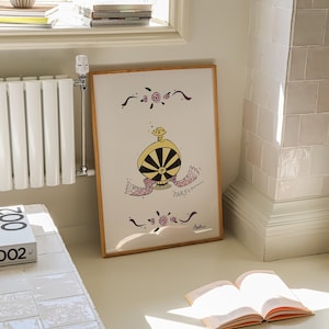 May include: A framed artwork featuring a whimsical illustration of a perfume bottle with a black and yellow design. The artwork includes the word "PARFUM" and decorative floral elements. The frame is made of light-colored wood.