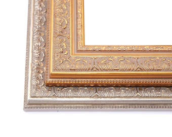 May include: A double picture frame with an ornate gold outer frame and a silver inner frame. The frame has a decorative design with a raised edge.