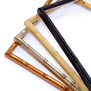 May include: Four picture frames made of wood with a bamboo design. The frames are in different colors: gold, silver, light brown, and black.