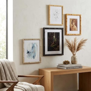 May include: A gallery wall arrangement featuring four rectangular picture frames with bamboo-style detailing. The frames contain a black and white floral line drawing, a portrait of a person, a blue watercolor abstract, and a dark forest landscape.
