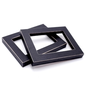 May include: Two black picture frames stacked on top of each other. The frames are made of wood and have a distressed finish.