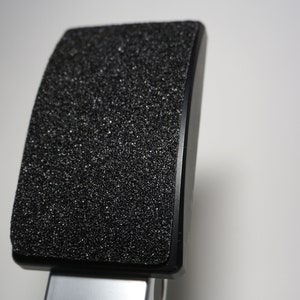 Könnte beinhalten: Eine schwarze und silberne Klemme mit einem strukturierten schwarzen Gummifuß. Die Klemme ist so konzipiert, dass sie Gegenstände festhält.