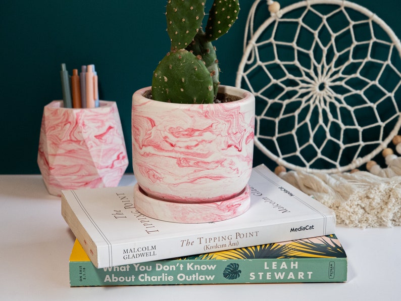 a pink concrete planter on top of books and a pink concrete pen holder