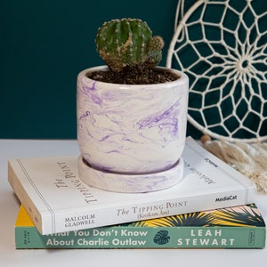 a purple concrete planter on top of books