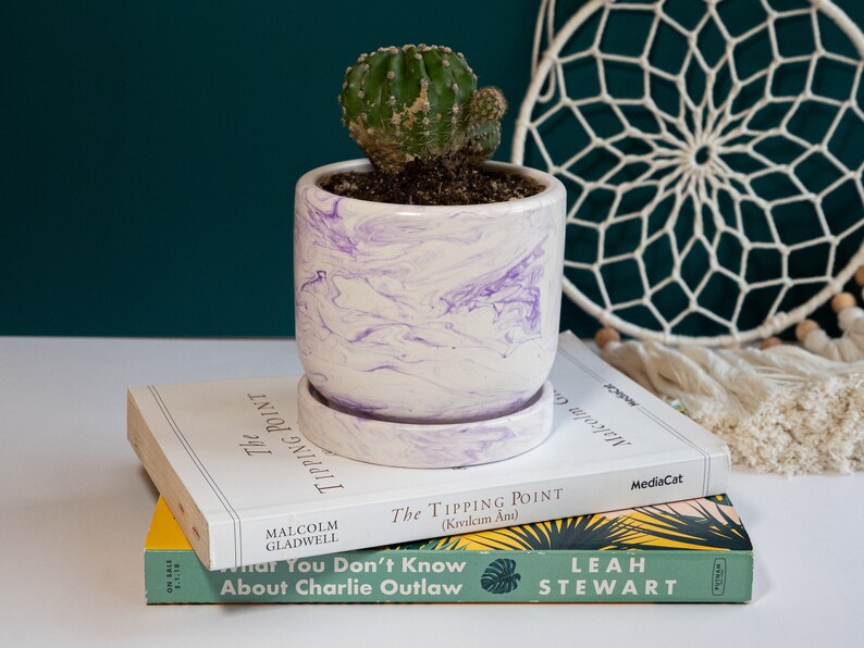 a purple concrete planter on top of books