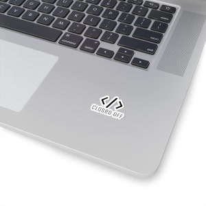 May include: A silver laptop computer with a white sticker on the top of the lid. The sticker has a black angled bracket symbol and the text "CLOSED OFF".