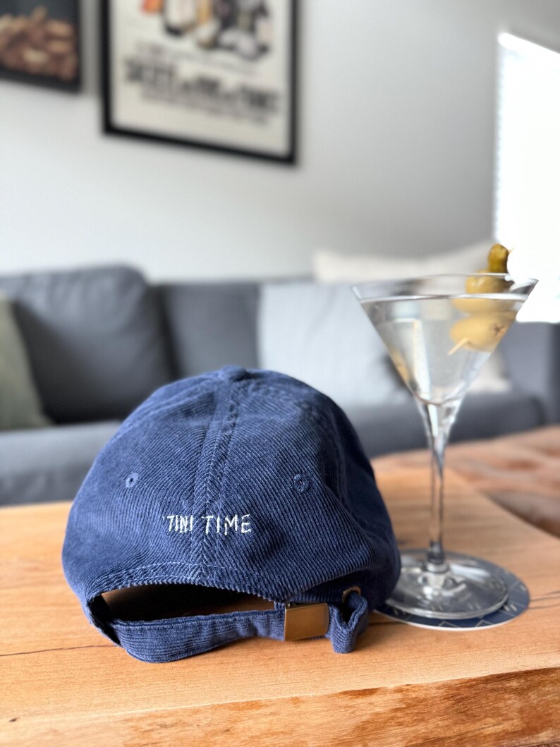 以下が含まれることがあります： 後ろに「TINI TIME」と刺繍されたネイビーのコーデュロイ製のベースボールキャップです。