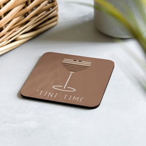 Può includere: Un sottobicchiere quadrato marrone con un contorno bianco di un bicchiere da martini e il testo "TINI TIME" in bianco.