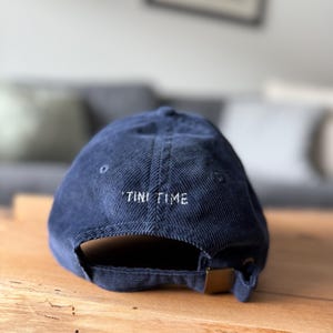 以下が含まれることがあります： 後ろに「TINI TIME」と刺繍されたネイビーのコーデュロイ製のベースボールキャップです。