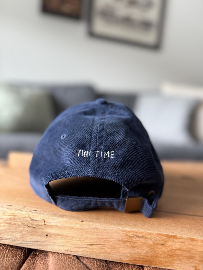 以下が含まれることがあります： 後ろに「TINI TIME」と刺繍されたネイビーのコーデュロイ製のベースボールキャップです。
