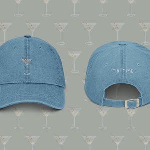 Op de afbeelding: Een blauwe denim baseballcap met een geborduurd martini-glas aan de voorkant en de tekst "TINI TIME" geborduurd aan de achterkant.