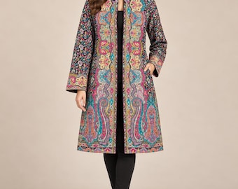 May include: A long-sleeved, knee-length coat featuring a vibrant, multi-colored paisley and floral pattern in shades of teal, magenta, yellow, and black. The coat has a structured collar, a straight open front, and side pockets, worn over black pants.