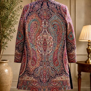 May include: A long-sleeved jacket featuring a dark navy blue base with an intricate, multi-colored paisley pattern in shades of red, pink, teal, and cream. The garment has a high collar, a structured fit, and a symmetrical design on the back.