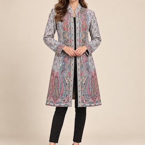 May include: A knee-length open-front coat featuring a vibrant multi-colored paisley pattern in shades of red, blue, and cream. The coat has long sleeves, a structured mandarin collar, and a straight silhouette, worn over a black top and black trousers.