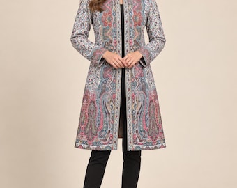 May include: A knee-length open-front coat featuring a vibrant multi-colored paisley pattern in shades of red, blue, and cream. The coat has long sleeves, a structured mandarin collar, and a straight silhouette, worn over a black top and black trousers.