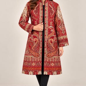 May include: A long-sleeved, knee-length coat featuring a vibrant red base with intricate, multi-colored paisley and geometric patterns throughout. The garment has a high collar, a straight open front, and black trim along the edges and inner lining.