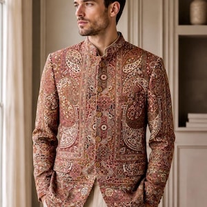 Op de afbeelding: Een blazer met lange mouwen, een opstaande kraag en een complex, veelkleurig paisley- en bloemenpatroon in tinten donkerrood, bruin en crème. Het jasje heeft een knoopsluiting aan de voorzijde met vijf zichtbare knopen en twee zakken.