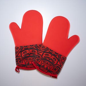 May include: A pair of red silicone oven mitts with a black and red patterned design. The pattern features stylized figures and geometric shapes.