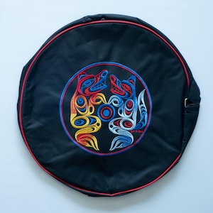 May include: Black round drum bag with a red, yellow, blue and white embroidered design of two wolves facing each other.
