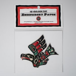May include: An embroidered patch featuring a stylised black, red, green and white bird with outstretched wings. The patch is packaged in a clear plastic bag with a header card that reads "Golden Top Embroidery Patch".