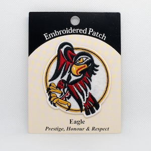 May include: Embroidered patch featuring a stylized eagle design with red, black, and yellow accents. The patch is on a cream-colored backing with the words "Embroidered Patch," "Eagle," and "Prestige, Honour & Respect."