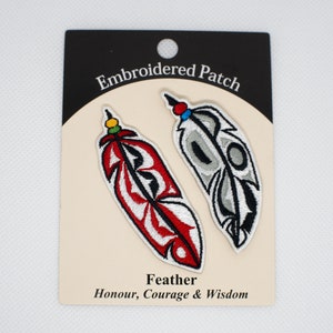 May include: Two embroidered patches featuring stylised feathers with red, white and black designs. The text "Embroidered Patch" and "Feather Honour, Courage & Wisdom" is printed on the card.